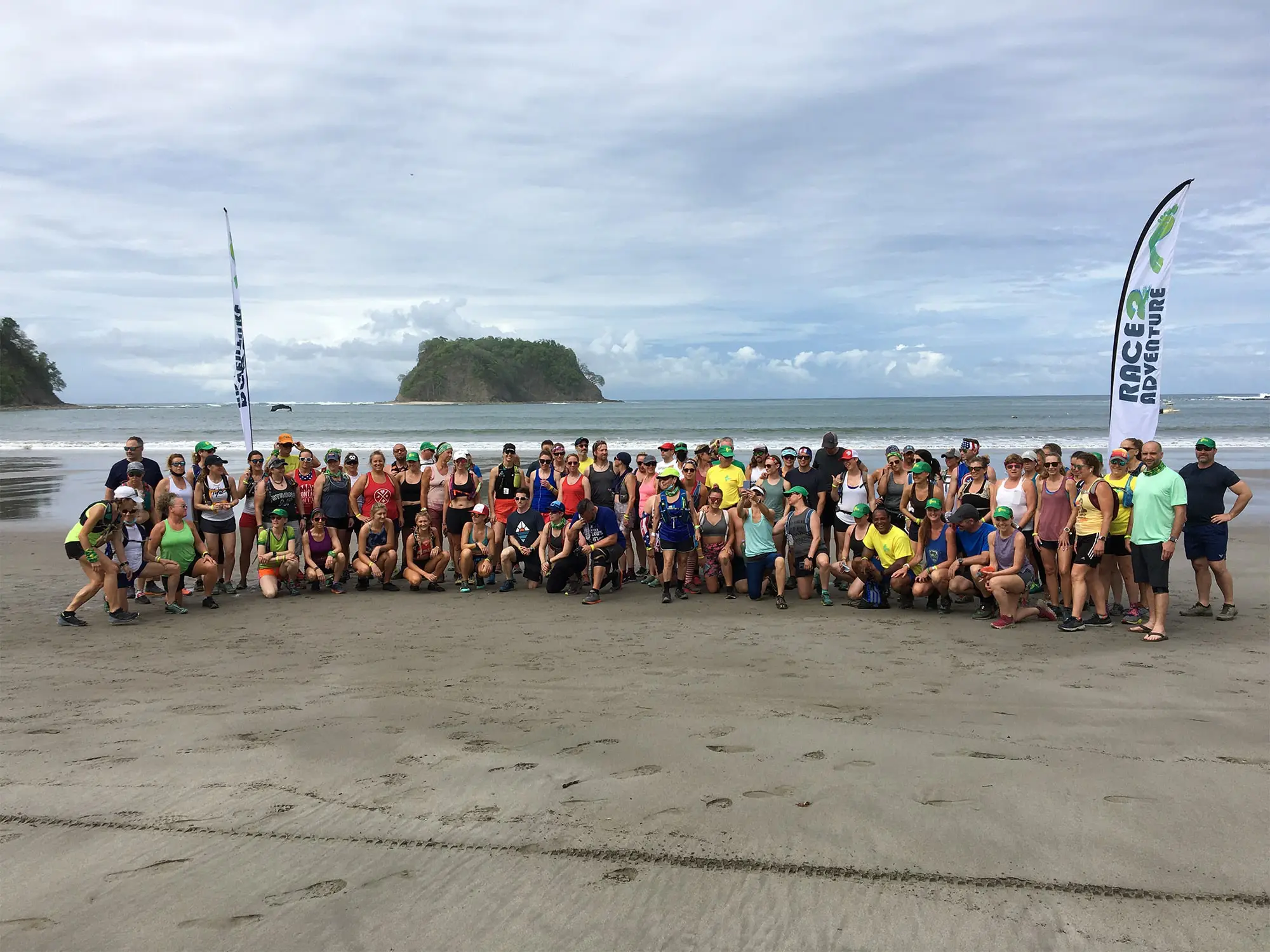 Large group of runners pose on the beach with local guides.