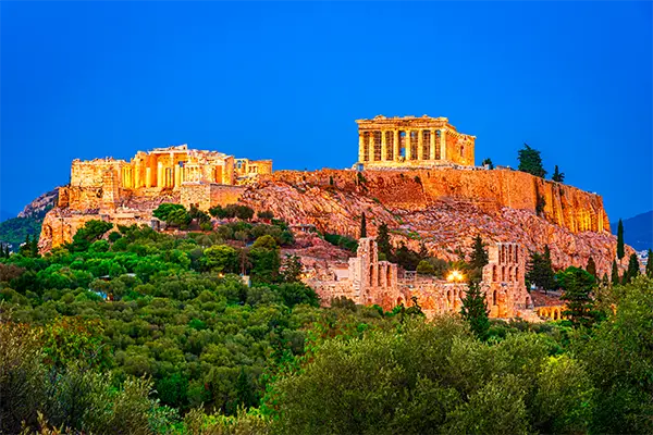 Race2Adventure Greece 2028 global vacation adventure illuminated Acropolis viewed from below at dusk. Run, seek, adventure!