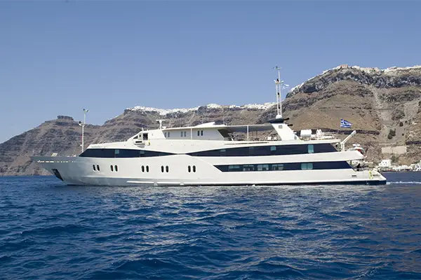 Race2Adventure Greece 2028 global vacation adventure exterior view of yacht off the shore of a greek isle on a sunny day. Run, seek, adventure!