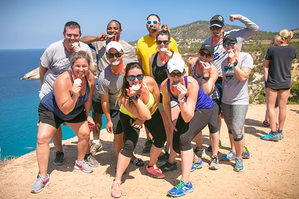 Race2Adventure Greece 2028 global vacation adventure smiling group bites olympic medals on a sunny beach. Run, seek, adventure!