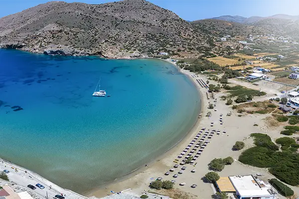 Race2Adventure Greece 2028 global vacation adventure aerial view of a white ship anchored in turquoise waters off the Greek island Syros on a sunny day. Run, seek, adventure!